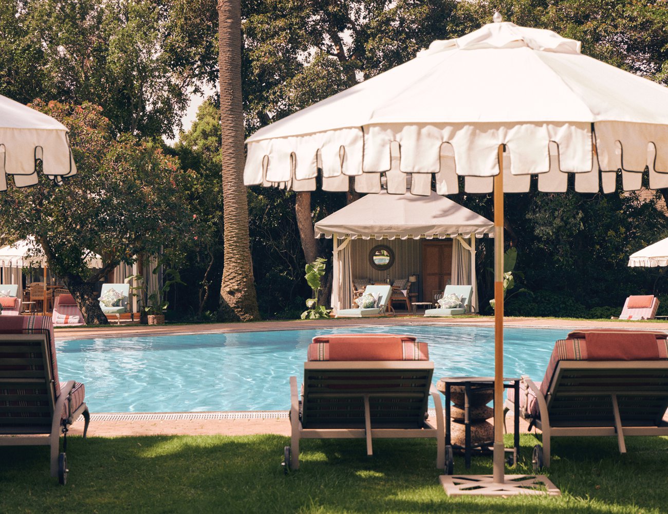 Poolside cabanas shaded by fringed umbrellas