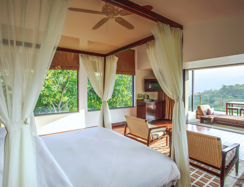 The bedroom in a forest villa opens out onto a balcony with uninterrupted vistas of the valley