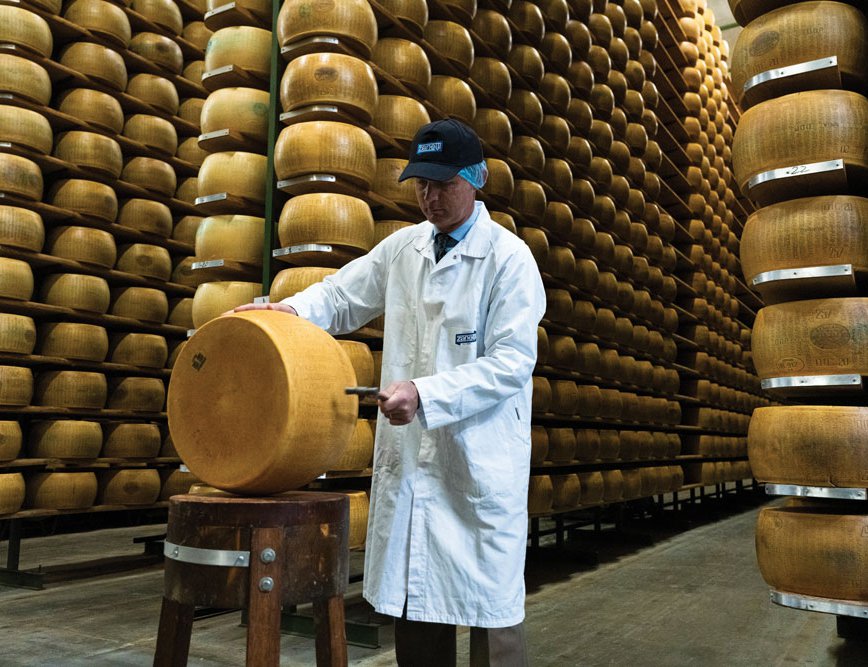 Paolo Zanetti knocks a wheel of Parmigiano Reggiano with a small hammer to check for holes or cracks in the cheese